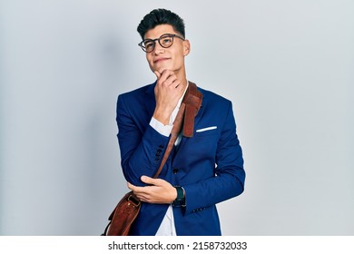 Young hispanic man wearing business clothes with hand on chin thinking about question, pensive expression. smiling with thoughtful face. doubt concept.  - Powered by Shutterstock