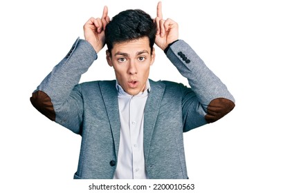 Young Hispanic Man Wearing Business Clothes Doing Funny Gesture With Finger Over Head As Bull Horns 