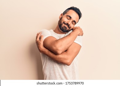 Young Hispanic Man Wearing Casual Clothes Hugging Oneself Happy And Positive, Smiling Confident. Self Love And Self Care 