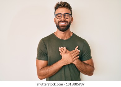 Young hispanic man wearing casual clothes and glasses smiling with hands on chest with closed eyes and grateful gesture on face. health concept. 