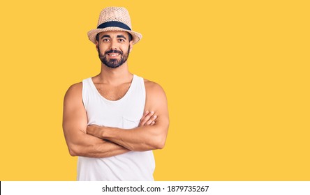 Young Hispanic Man Wearing Casual Summer Hat Happy Face Smiling With Crossed Arms Looking At The Camera. Positive Person. 