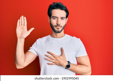 Young hispanic man wearing casual white tshirt swearing with hand on chest and open palm, making a loyalty promise oath 