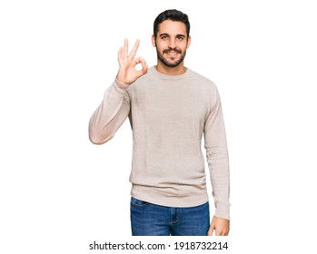 Young hispanic man wearing casual clothes smiling positive doing ok sign with hand and fingers. successful expression. 