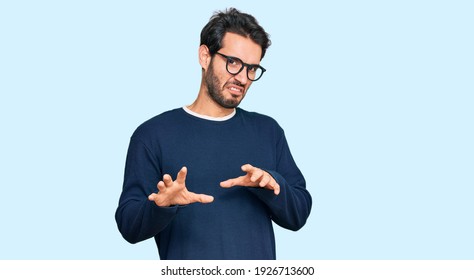Junge hispanische Mann mit beiläufigen Kleidung und Brille widerte Ausdruck, verärgert und ängstlich tun Ekel Gesicht, weil Aversion Reaktion. mit Händen aufgezogen 