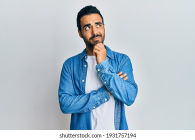 Young hispanic man wearing casual clothes thinking concentrated about doubt with finger on chin and looking up wondering 
