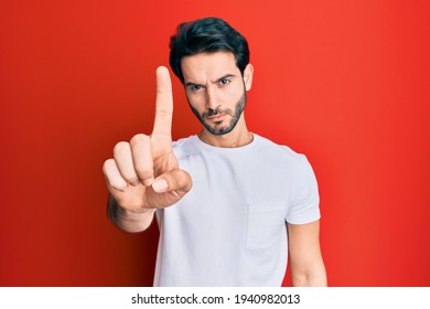 Young Hispanic Man Wearing Casual White Tshirt Pointing With Finger Up And Angry Expression, Showing No Gesture 