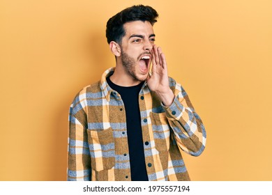 Young Hispanic Man Wearing Casual Clothes Shouting And Screaming Loud To Side With Hand On Mouth. Communication Concept. 