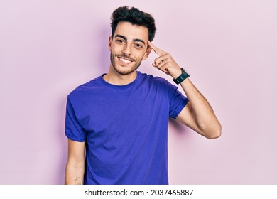 Young hispanic man wearing casual t shirt smiling pointing to head with one finger, great idea or thought, good memory  - Powered by Shutterstock