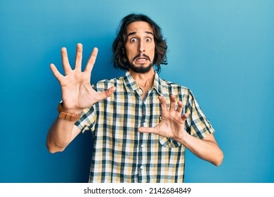 Young hispanic man wearing casual clothes afraid and terrified with fear expression stop gesture with hands, shouting in shock. panic concept. 