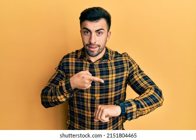 Young hispanic man wearing casual clothes in hurry pointing to watch time, impatience, upset and angry for deadline delay 