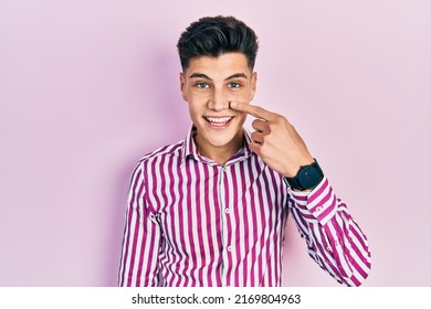 Young Hispanic Man Wearing Casual Clothes Pointing With Hand Finger To Face And Nose, Smiling Cheerful. Beauty Concept 