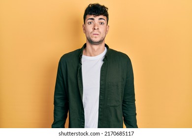 Young hispanic man wearing casual clothes puffing cheeks with funny face. mouth inflated with air, crazy expression.  - Shutterstock ID 2170685117
