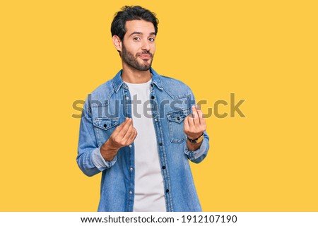 Young hispanic man wearing casual clothes doing money gesture with hands, asking for salary payment, millionaire business 