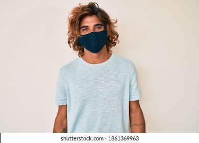 Young Hispanic Man Wearing Covid-19 Mask With A Happy And Cool Smile On Face. Lucky Person. 