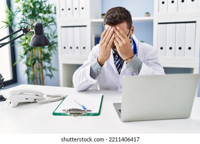 Young Hispanic Man Wearing Doctor Uniform Stressed Working At Clinic