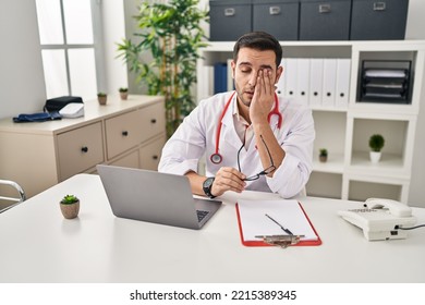 Young Hispanic Man Wearing Doctor Uniform Stressed Working At Clinic