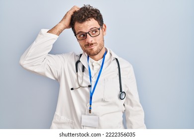 Young hispanic man wearing doctor uniform and stethoscope confuse and wonder about question. uncertain with doubt, thinking with hand on head. pensive concept.  - Powered by Shutterstock