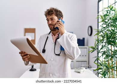 Young hispanic man wearing doctor uniform reading diagnosis talking on the smartphone at clinic - Powered by Shutterstock