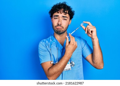 Young Hispanic Man Wearing Nurse Uniform Holding Vaccine Depressed And Worry For Distress, Crying Angry And Afraid. Sad Expression. 