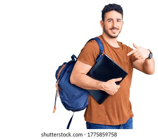 Young Hispanic Man Wearing Student Backpack Holding Binder Smiling Happy Pointing With Hand And Finger 