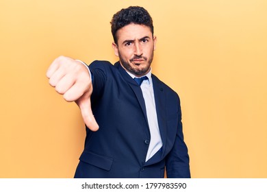 Young Hispanic Man Wearing Suit Looking Unhappy And Angry Showing Rejection And Negative With Thumbs Down Gesture. Bad Expression. 