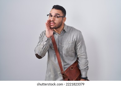 Young Hispanic Man Wearing Suitcase Hand On Mouth Telling Secret Rumor, Whispering Malicious Talk Conversation 