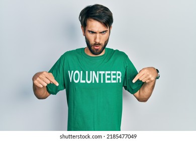 Young Hispanic Man Wearing Volunteer T Shirt Pointing Down With Fingers Showing Advertisement, Surprised Face And Open Mouth 