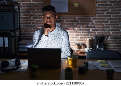 Young hispanic man working at the office at night with hand on chin thinking about question, pensive expression. smiling with thoughtful face. doubt concept.  - Shutterstock ID 2211389859