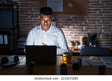 Young hispanic man working at the office at night with hand on stomach because indigestion, painful illness feeling unwell. ache concept.  - Shutterstock ID 2214272283