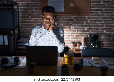Young hispanic man working at the office at night touching mouth with hand with painful expression because of toothache or dental illness on teeth. dentist  - Shutterstock ID 2273441503