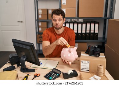 Young Hispanic Man Working At Small Business Ecommerce Holding Piggy Bank Depressed And Worry For Distress, Crying Angry And Afraid. Sad Expression. 