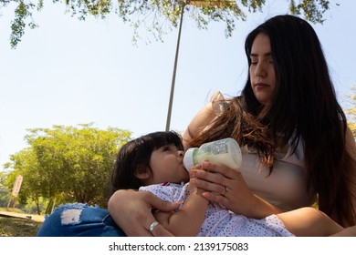 Young Hispanic Mother Feeding Her Baby With A Bottle