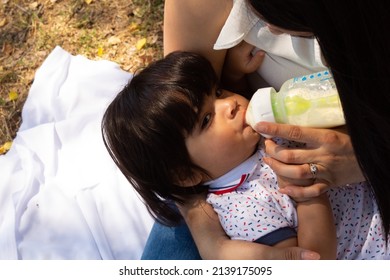 Young Hispanic Mother Feeding Her Baby With A Bottle