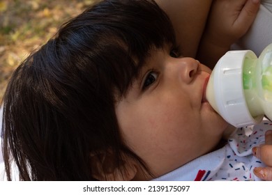 Young Hispanic Mother Feeding Her Baby With A Bottle