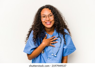 Young Hispanic Nurse Woman Isolated On White Background Laughs Out Loudly Keeping Hand On Chest.