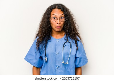 Young Hispanic Nurse Woman Isolated On White Background Shrugs Shoulders And Open Eyes Confused.