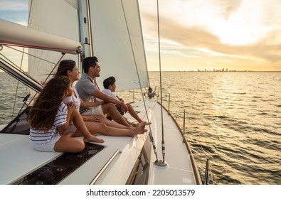 Young Hispanic Parents With Son And Daughter Relaxing At Sunset On Luxury Family Vacation Sailing On Private Yacht