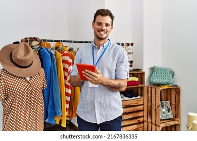 Young hispanic shopkeeper man smiling happy using touchpad working at clothing store. - Powered by Shutterstock