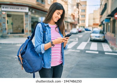 Young hispanic student girl smiling happy using smartphone at the city. - Powered by Shutterstock