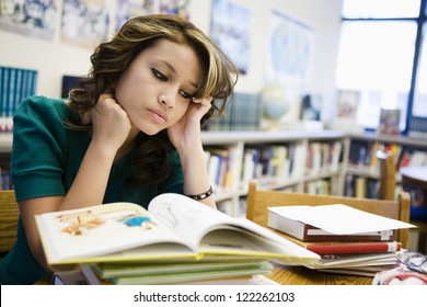 Young Hispanic student reading books in library
