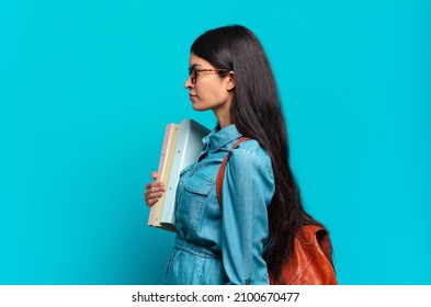 Young Hispanic Student Woman On Profile View Looking To Copy Space Ahead, Thinking, Imagining Or Daydreaming