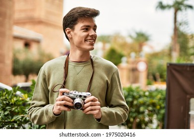 Young Hispanic Tourist Man Smiling Happy Using Vintage Camera At The City.