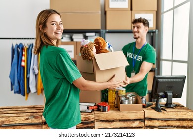 Young hispanic volunteer couple smiling happy giving box with toys to donate at charity center. - Powered by Shutterstock