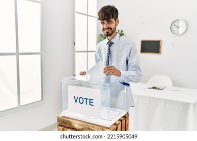 Young Hispanic Voter Man Putting Vote In Ballot At Electoral College.