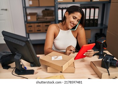 Young Hispanic Woman Business Worker Using Touchpad And Taking On The Smartphone At Office