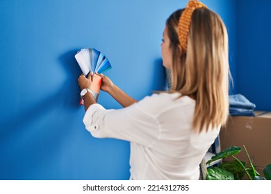 Young Hispanic Woman Choosing Wall Paint Color At New Home