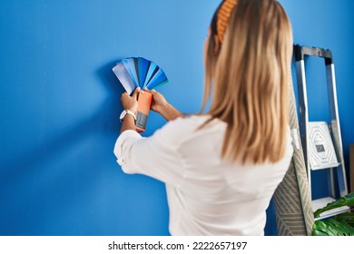 Young Hispanic Woman Choosing Wall Paint Color At New Home