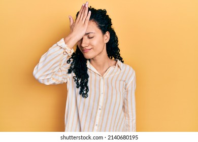 Young Hispanic Woman With Curly Hair Wearing Casual Striped Shirt Surprised With Hand On Head For Mistake, Remember Error. Forgot, Bad Memory Concept. 