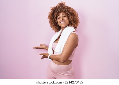 Young Hispanic Woman With Curly Hair Wearing Sportswear And Towel Inviting To Enter Smiling Natural With Open Hand 