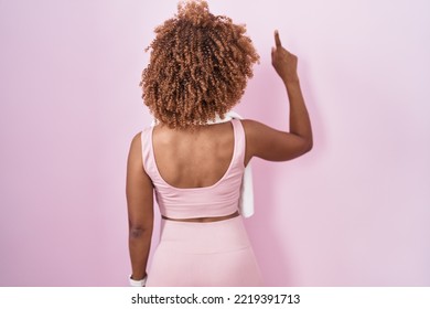 Young Hispanic Woman With Curly Hair Wearing Sportswear And Towel Posing Backwards Pointing Ahead With Finger Hand 